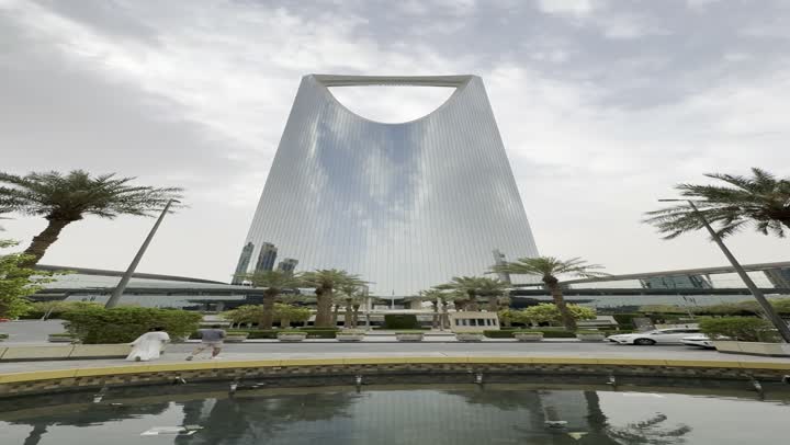 The concept of growth, progress, and modern urban development, a slow-motion shot from top to bottom of the famous Kingdom Tower in Riyadh, the towers and skyscrapers, the buildings and famous commercial landmarks in Saudi Arabia, the architectural engineering art in a modern and advanced style.