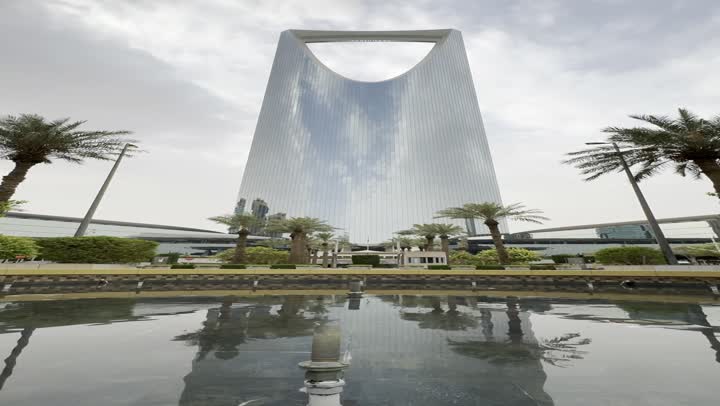 حركة المرور في محيط برج المملكة، الاندماج مع الطبيعة وجود أشجار خضراء، تصوير لبرج المملكة الشهير في مدينة الرياض، الأبراج وناطحات السحاب، المباني والمعالم التجارية المشهورة في السعودية، الفن الهندسي المعماري على الطراز المتطور والحديث
