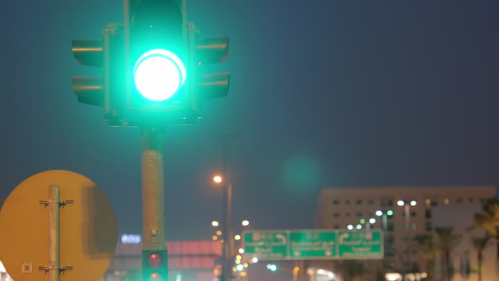 Road and traffic networks, a close-up shot of a lit traffic signal to organize traffic on the streets and roads of Riyadh at night, adherence to traffic regulations in the Kingdom of Saudi Arabia.