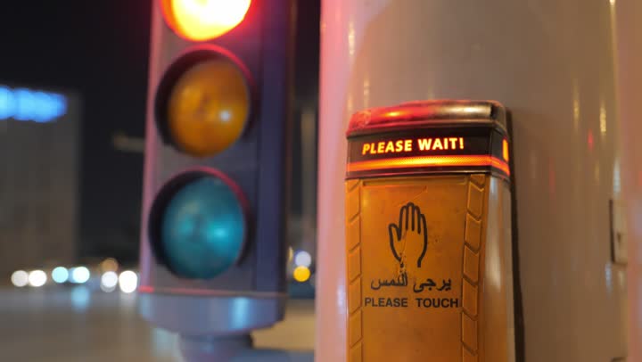 Adhering to traffic guidelines in the Kingdom of Saudi Arabia, road and traffic networks, a close-up shot of a lit pedestrian traffic signal to organize traffic in the streets and roads of Riyadh at night.