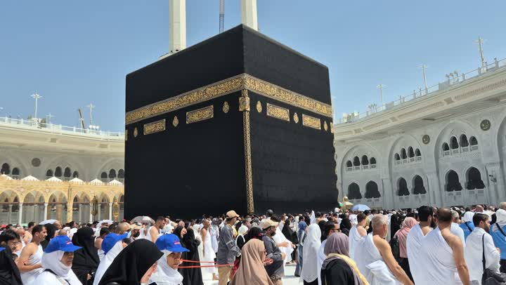 مقصد المسلمين من أنحاء العالم قبلة الاسلام والمسلمين، مكان ومعلم إسلامي ديني مقدس في السعودية، تصوير مقرب لالحجاج والمعتمرين يطوفون حول الكعبة المشرفة في مكة المكرمة، مفهوم العبادة والتقرب إلى الله، برج المملكة والابراج الفندقية المطلة على الحرم