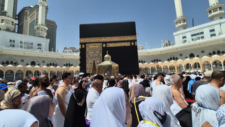 مقصد المسلمين من أنحاء العالم قبلة الاسلام والمسلمين، مكان ومعلم إسلامي ديني مقدس في السعودية، تصوير مقرب لالحجاج والمعتمرين يطوفون حول الكعبة المشرفة في مكة المكرمة، مفهوم العبادة والتقرب إلى الله، برج المملكة والابراج الفندقية المطلة على الحرم