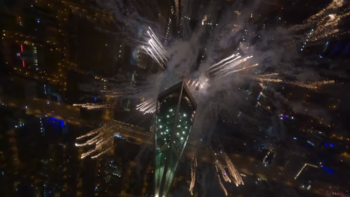 Fireworks and pyrotechnics in the night sky, aerial drone footage of a famous tourist attraction in Riyadh, the economic and urban renaissance of the capital's skyline, the architectural engineering art of towers and skyscrapers, the growth and urban development in the capital of the Kingdom of Saudi Arabia.