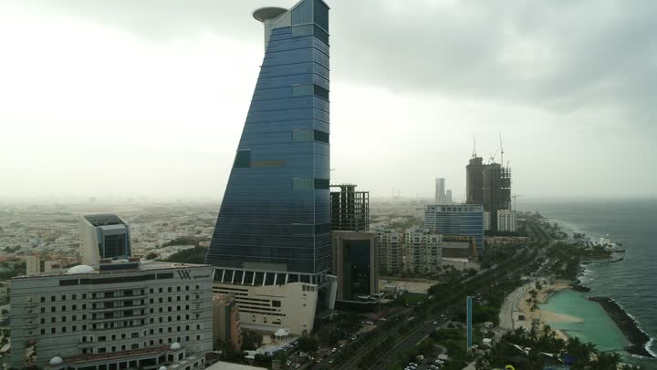 الواجهة البحرية  لكورنيش جدة في المملكة العربية السعودية الفن الهندسي المعماري للمنشآت التجارية المطلة عليها، تصوير درون مقرب لمبنى برج الكورنيش في مدينة جدة, الاستمتاع بالمناظر الطبيعية المائية، الأبراج وناطحات السحاب في المدينة الساحلية