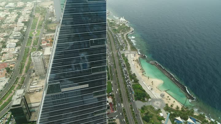 الواجهة البحرية  لكورنيش جدة في المملكة العربية السعودية الفن الهندسي المعماري للمنشآت التجارية المطلة عليها، تصوير درون مقرب لمبنى برج الكورنيش في مدينة جدة, الاستمتاع بالمناظر الطبيعية المائية، الأبراج وناطحات السحاب في المدينة الساحلية