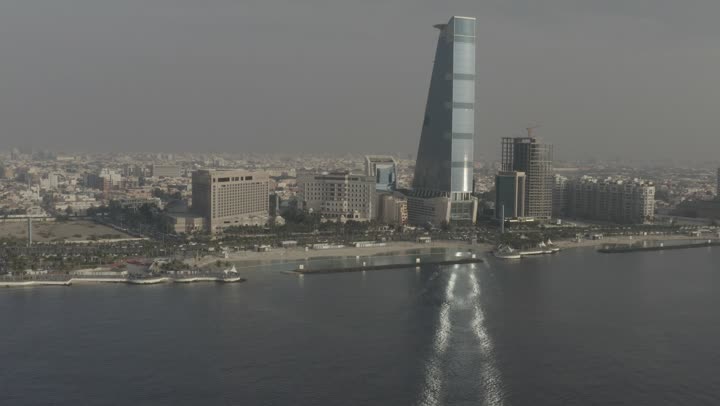 A famous place and tourist attraction on the Red Sea beach, the waterfront of the Jeddah Corniche in the Kingdom of Saudi Arabia, showcasing the architectural engineering of the commercial establishments overlooking it, drone photography after sunset of the Corniche Tower building and the movement of the Murooj in the city of Jeddah.