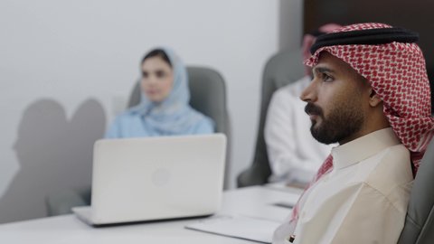 مشاهدة عرض تقديمي عن المشروع، بيئة العمل المريحة في الشركات السعودية، استخدام الأجهزة التقنية الحديثة في المكاتب، مناقشات لتحقيق الاستراتيجيات والغايات، اجتماع عمل موظفين عرب خليجيين سعوديين في غرفة الاجتماعات، التفاهم والتعاون بين الزملاء لتحقيق أهداف الشركة