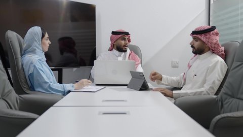 بيئة العمل المريحة في الشركات السعودية، استخدام الأجهزة التقنية الحديثة في المكاتب، مناقشات و حوارات لتحقيق الاستراتيجيات والغايات، اجتماع عمل بين موظفين عرب خليجيين سعوديين في غرفة الاجتماعات، التفاهم والتعاون بين الزملاء لتحقيق أهداف الشركة
