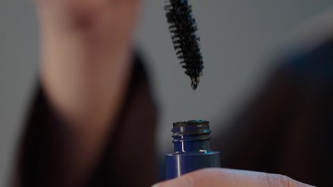 استخدام الماسكرا لإبراز جمال العينين، الإهتمام بالجمال والمظهر الخارجي، دورات تعليمية لمكياج تتوريال, المستحضرات التجميل النسائية، بورتريه مقرب ليد امراة عربية خليجية سعودية  تقوم بوضع الميكاب، خلفيه رمادية