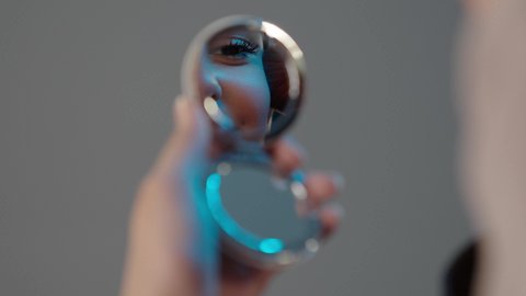 The use of cosmetics, attention to external appearance, the concept of adornment and beautification, marketing of cosmetic products, a close-up portrait of the hand of a Saudi Gulf Arab woman using a blush box and brush, gray background.