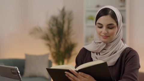 ايماءات التركيز و الاندماج، مراجعة الدروس اليومية، مفهوم الاجتهاد والتفوق والنجاح, تصوير مقرب لطالبة جامعية عربية خليجية سعودية محجبة ترتدي العباءة تقوم بمذاكرة الكتاب الجامعي