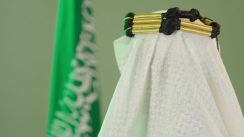 ذكرى تأسيس الدولة السعودية الأولى في 22 فبراير،  يوم العلم ١١ مارس ،  بورتريه من الخلف لرجل عربي سعودي خليجي يرتدي البشت والغتره وعقال يوم التأسيس يرفع علم السعوديه وينطر للكاميرا ، يوم بدينا 1727م ، تذكار اليوم الوطني السعودي 23 سبتمبر