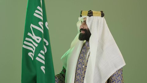 The anniversary of the founding of the first Saudi state on February 22, Flag Day on March 11, Saudi National Day on September 23, a portrait of a Saudi Arabian Gulf man wearing a bisht, ghutra, and agal on Founding Day raising the Saudi flag, the day we began 1727 AD