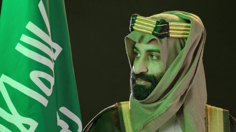 Flag Day, March 11, portrait of a Saudi Arabian Gulf man wearing a bisht, ghutra, and agal. Founding Day raising the Saudi flag. The day we began in 1727 AD. Saudi National Day commemorates September 23, the anniversary of the founding of the first Saudi state on February 22.