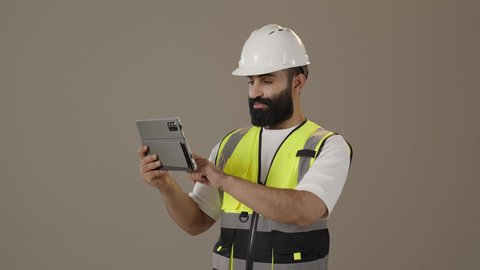 دمج التقنيات الحديثة و المتطورة بالأعمال الهندسية, العمل في القطاع الهندسي, تطور و نمو مجال الهندسة في المملكة العربية السعودية, مهندس عربي خليجي سعودي يرتدي سترة و خوذة الحماية يحمل بيديه الجهاز اللوحي