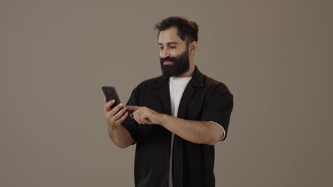 استخدام الأجهزة والتقنيات الحديثة والمتطورة، تصفح التطبيقات وبرامج التواصل الاجتماعي، تبادل الأحاديث مع الأهل والأصدقاء، بورتريه لرجل عربي سعودي خليجي يرتدي الزى الكاجوال يمسك بيده الجوال