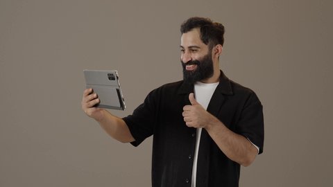 Spending free time practicing hobbies, portrait of a Saudi Arabian Gulf man wearing casual clothes holding a tablet in his hands, using technology in entertainment, chatting via tablet