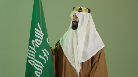 يوم العلم ١١ مارس ، تذكار اليوم الوطني السعودي 23 سبتمبر،ذكرى تأسيس الدولة السعودية الأولى في 22 فبراير، بورتريه لرجل عربي سعودي خليجي يرتدي البشت والغتره وعقال يوم التأسيس يرفع علم السعوديه، يوم بدينا 1727م