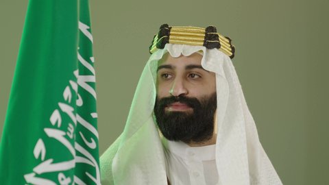 The anniversary of the founding of the first Saudi state on February 22, the day we began in 1727 AD, the commemoration of Saudi National Day on September 23, a portrait of a Saudi Arabian Gulf man wearing a bisht, ghutra, and agal on the founding day raising the Saudi flag, Flag Day on March 11