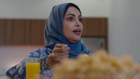 افطار الصائم وقت أذان المغرب في رمضان، أجواء دينية رمضانية، عائلة عربية خليجية سعودية تجلس حول مائدة الطعام في المنزل، سفرة مليئة بالمأكولات الشهية، اجتماع الأسرة حول مائدة الطعام