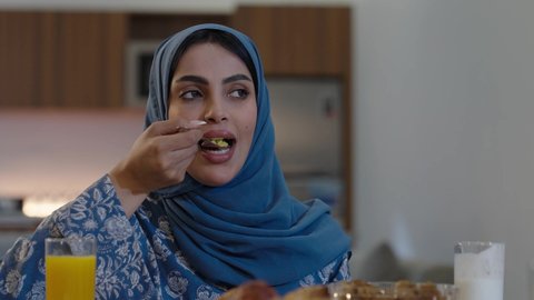 أجواء دينية رمضانية، عائلة عربية خليجية سعودية تجلس حول مائدة الطعام في المنزل، سفرة مليئة بالمأكولات الشهية، اجتماع الأسرة حول مائدة الطعام، افطار الصائم وقت أذان المغرب في رمضان