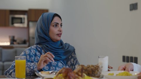 اجتماع الأسرة حول مائدة الطعام، افطار الصائم وقت أذان المغرب في رمضان، أجواء دينية رمضانية، عائلة عربية خليجية سعودية تجلس حول مائدة الطعام في المنزل، سفرة مليئة بالمأكولات الشهية