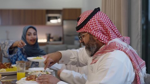 اجتماع الأسرة حول مائدة الطعام، افطار الصائم وقت أذان المغرب في رمضان، أجواء دينية رمضانية، عائلة عربية خليجية سعودية تجلس حول مائدة الطعام في المنزل، سفرة مليئة بالمأكولات الشهية