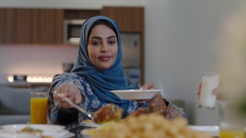 افطار الصائم وقت أذان المغرب في رمضان، أجواء دينية رمضانية، عائلة عربية خليجية سعودية تجلس حول مائدة الطعام في المنزل، سفرة مليئة بالمأكولات الشهية، اجتماع الأسرة حول مائدة الطعام