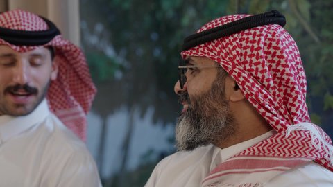 أجواء دينية رمضانية، عائلة عربية خليجية سعودية تجلس حول مائدة الطعام في المنزل، سفرة مليئة بالمأكولات الشهية، اجتماع الأسرة حول مائدة الطعام، افطار الصائم وقت أذان المغرب في رمضان