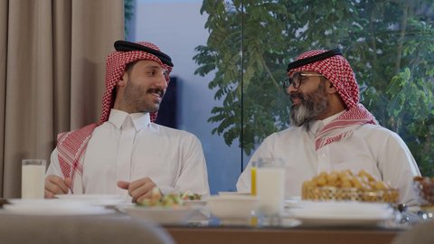  سفرة مليئة بالمأكولات الشهية، اجتماع الأسرة حول مائدة الطعام، افطار الصائم وقت أذان المغرب في رمضان، أجواء دينية رمضانية، عائلة عربية خليجية سعودية تجلس حول مائدة الطعام في المنزل