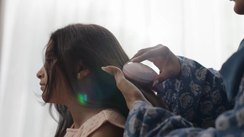  العناية والاهتمام بالأناقة والمظهر الخارجي، إيماءات السعادة والسرور، المحافظة على شعر صحي وأنيق، امراة عربية خليجية سعودية ترتدي العباءة والحجاب تجلس على الكنبة تقوم بتصفيف وتمشيط شعر ابنتها باستخدام الفرشاة ( المشط ) 