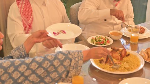  أجواء عائلية روحانية دينية إسلامية، اجتماع الأسرة حول مائدة الإفطار المليئة بأصناف المأكولات والمقبلات الشهية، موعد كسر الصيام عند أذان المغرب في رمضان المبارك، فطور رمضاني عائلي، عائلة عربية خليجية سعودية تجلس بايماءات السرور، حسن الضيافة وإكرام الأخرين