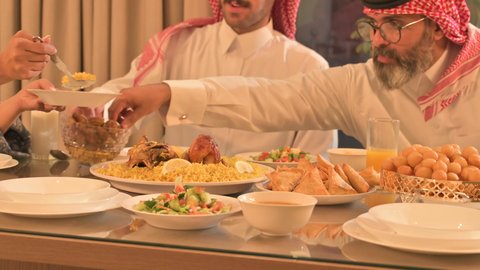  حسن الضيافة وإكرام الأخرين, أجواء عائلية روحانية دينية إسلامية، اجتماع الأسرة حول مائدة الإفطار المليئة بأصناف المأكولات والمقبلات الشهية، موعد كسر الصيام عند أذان المغرب في رمضان المبارك، فطور رمضاني عائلي، عائلة عربية خليجية سعودية تجلس بايماءات السرور