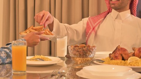  فطور رمضاني عائلي، عائلة عربية خليجية سعودية تجلس بايماءات السرور، حسن الضيافة وإكرام الأخرين, أجواء عائلية روحانية دينية إسلامية، اجتماع الأسرة حول مائدة الإفطار المليئة بأصناف المأكولات والمقبلات الشهية، موعد كسر الصيام عند أذان المغرب في رمضان المبارك