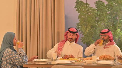  حسن الضيافة وإكرام الأخرين, أجواء عائلية روحانية دينية إسلامية، اجتماع الأسرة حول مائدة الإفطار المليئة بأصناف المأكولات والمقبلات الشهية، موعد كسر الصيام عند أذان المغرب في رمضان المبارك، فطور رمضاني عائلي، عائلة عربية خليجية سعودية تجلس بايماءات السرور