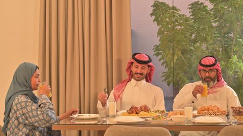  حسن الضيافة وإكرام الأخرين, أجواء عائلية روحانية دينية إسلامية، اجتماع الأسرة حول مائدة الإفطار المليئة بأصناف المأكولات والمقبلات الشهية، موعد كسر الصيام عند أذان المغرب في رمضان المبارك، فطور رمضاني عائلي، عائلة عربية خليجية سعودية تجلس بايماءات السرور