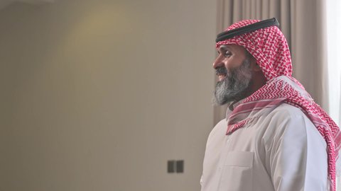 عادات وتقاليد المجتمع السعودي في الأعياد والمناسبات الاسلامية، الاصالة والعراقة والتراث السعودي, عطورات وروائح خليجية مميزة، تصوير من الجانب لرجل شايب كبير بالسن عربي خليجي سعودي يرتدي الثوب التقليدي والشماغ يقوم بتبخير نفسه بالمبخرة، التبخر والتطيب بخشب العود