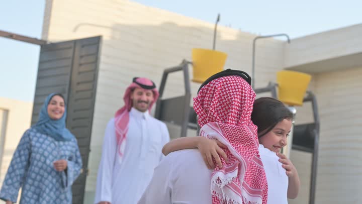 شاليه ومنتجع ترفيهي في المملكة، الاستمتاع بالإجازة الصيفية برفقة العائلة، ايماءات السعادة والسرور، قضاء وقت ممتع ومنعش في فصل الصيف، الأجواء العائلية المليئة بالحب، عائلة عربية خليجية سعودية مبتسمة تمشي في المنتزه