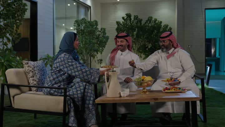 صلة الرحم والترابط الاسري, فرحة وبهجة الابناء في ايام العيد السعيد, التجمعات والزيارات الاسرية في الأعياد والمناسبات الاسلامية, رجل عربي خليجي سعودي يرتدي الزي التقليدي يجلس مع أحفاده بإيماءات الفرح والسرور، ضيافة وحلوى العيد، حسن استقبال وإكرام الضيف