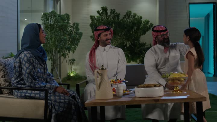 صلة الرحم والترابط الاسري, فرحة وبهجة الابناء في ايام العيد السعيد, التجمعات والزيارات الاسرية في الأعياد والمناسبات الاسلامية, رجل عربي خليجي سعودي يرتدي الزي التقليدي يجلس مع أحفاده بإيماءات الفرح والسرور، ضيافة وحلوى العيد، حسن استقبال وإكرام الضيف