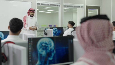 العلم والتعليم في المجتمع السعودي, إقامة دورات تدريبية للطلاب, متحدث ودكتور جامعي عربي خليجي سعودي يرتدي الشماغ والثوب التقليدي يقوم بإلقاء محاضرة أمام الطلبة, محاضرات ودورات تعليمية في السعودية، قاعة دراسية مجهزة بشاشات وأجهزة تقنية حديثة