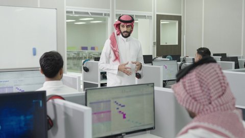 قاعة دراسية مجهزة بشاشات وأجهزة تقنية حديثة، العلم والتعليم في المجتمع السعودي, إقامة دورات تدريبية للطلاب, متحدث ودكتور جامعي عربي خليجي سعودي يرتدي الشماغ والثوب التقليدي يقوم بإلقاء محاضرة أمام الطلبة, محاضرات ودورات تعليمية في السعودية