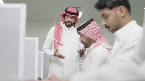 استخدام جهاز الحاسوب، التعليم العالي في الجامعات والكليات الأكاديمية, دمج التعلم مع التكنولوجيا، إجراء اختبارات وأبحاث العلمية، طلاب عرب خليجيون سعوديون يرتدون الزي التقليدي يقومون بحضور محاضرة في قاعة دراسية، جودة التعليم الجامعي في المملكة العربية السعودية