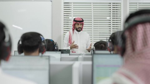 استخدام سماعات الرأس، قاعة دراسية مجهزة بشاشات وأجهزة تقنية حديثة، العلم والتعليم في المجتمع السعودي, إقامة دورات تدريبية للطلاب, متحدث ودكتور جامعي عربي خليجي سعودي يرتدي الشماغ والثوب التقليدي يقوم بإلقاء محاضرة أمام الطلبة, محاضرات ودورات تعليمية في السعودية