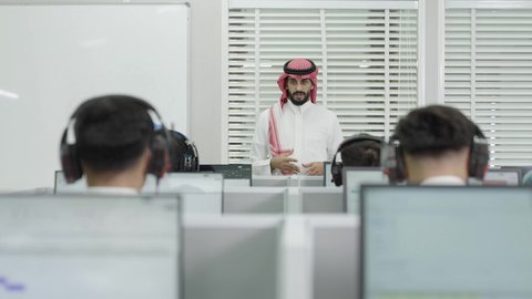 محاضرات ودورات تعليمية في السعودية، استخدام سماعات الرأس، قاعة دراسية مجهزة بشاشات وأجهزة تقنية حديثة، العلم والتعليم في المجتمع السعودي, إقامة دورات تدريبية للطلاب, متحدث ودكتور جامعي عربي خليجي سعودي يرتدي الشماغ والثوب التقليدي يقوم بإلقاء محاضرة أمام الطلبة