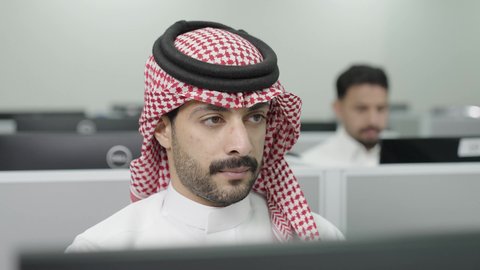 إيماءات التركيز والاندماج، دمج التعلم مع التكنولوجيا، التعليم العالي في الجامعات والكليات الأكاديمية, إجراء اختبارات وأبحاث علمية عبر الانترنت، طلاب عرب خليجيون سعوديون يرتدون الزي التقليدي يقومون باستخدام الحاسوب في قاعة دراسية، جودة التعليم الجامعي في المملكة