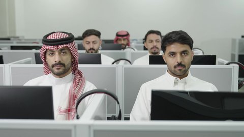 وضع سماعات الرأس، دمج التعلم مع التكنولوجيا، التعليم العالي في الجامعات والكليات الأكاديمية, إجراء اختبارات وأبحاث علمية عبر الانترنت، طلاب عرب خليجيون سعوديون يرتدون الزي التقليدي يقومون باستخدام الحاسوب في قاعة دراسية، جودة التعليم الجامعي في المملكة