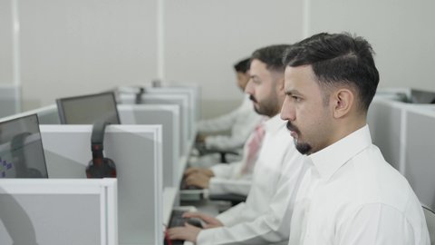 تعابير التركيز والاندماج، دمج التعلم مع التكنولوجيا، التعليم العالي في الجامعات والكليات الأكاديمية, إجراء اختبارات وأبحاث علمية عبر الانترنت، طلاب عرب خليجيون سعوديون يرتدون الزي التقليدي يقومون باستخدام الحاسوب في قاعة دراسية، جودة التعليم الجامعي في المملكة