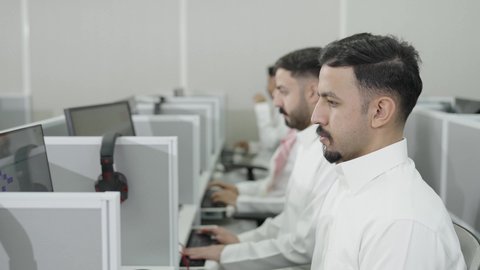 إيماءات التركيز والاندماج، دمج التعلم مع التكنولوجيا، التعليم العالي في الجامعات والكليات الأكاديمية, إجراء اختبارات وأبحاث علمية عبر الانترنت، طلاب عرب خليجيون سعوديون يرتدون الزي التقليدي يقومون باستخدام الحاسوب في قاعة دراسية، جودة التعليم الجامعي في المملكة