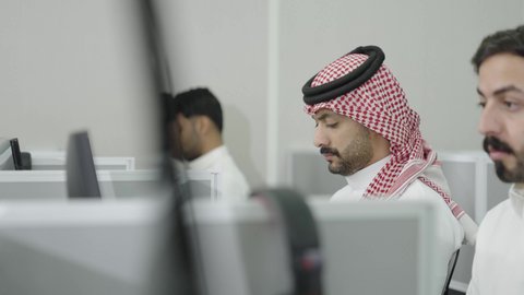 تعابير التركيز والاندماج، دمج التعلم مع التكنولوجيا، التعليم العالي في الجامعات والكليات الأكاديمية, إجراء اختبارات وأبحاث علمية عبر الانترنت، طلاب عرب خليجيون سعوديون يرتدون الزي التقليدي يقومون باستخدام الحاسوب في قاعة دراسية، جودة التعليم الجامعي في المملكة